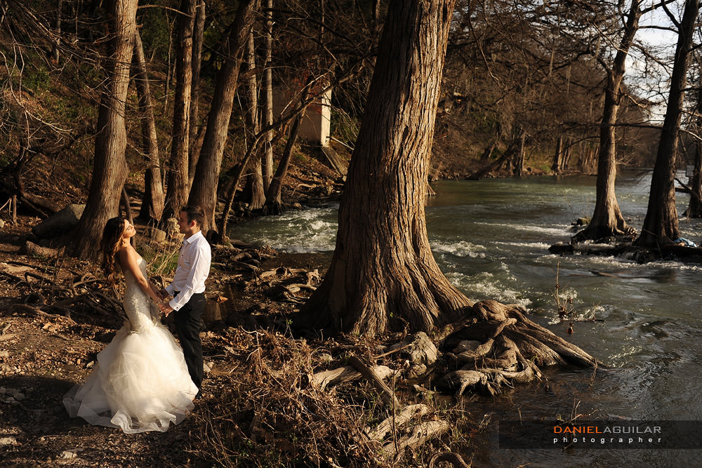 A bride and a groom holding hands at the shore of the Guadalupe River