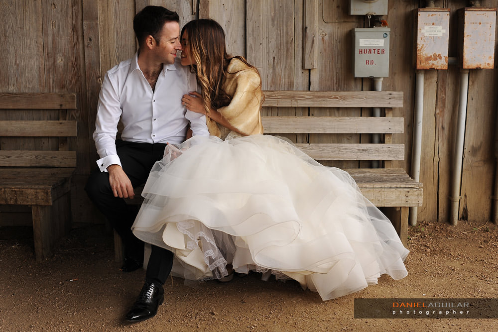 Gruene Texas photo shoot of bride and groom Bride and groom sitting on a bench and smiling in barn of Gruene TX