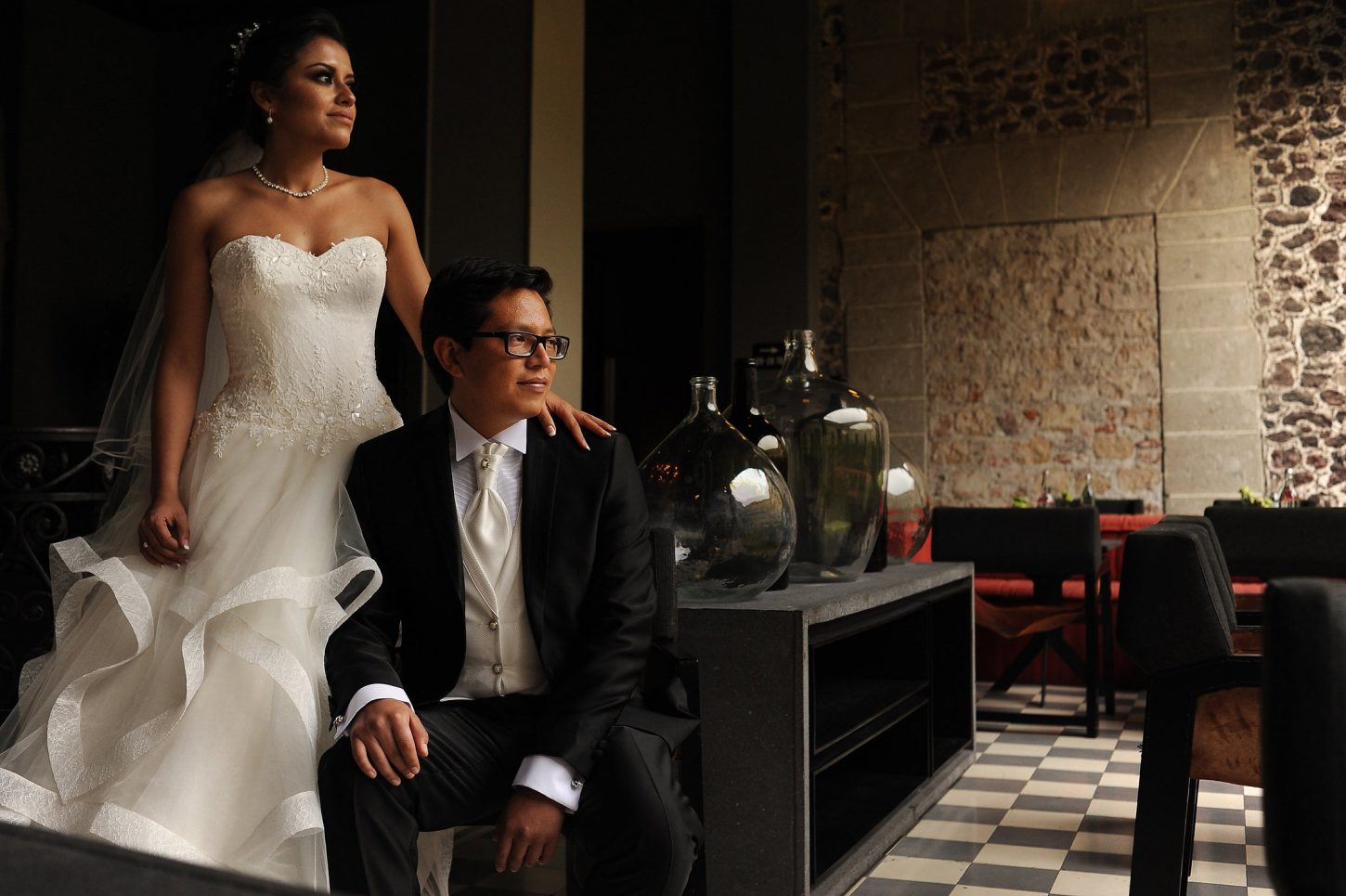 A bride and groom pose for a formal picture in hotel lobby