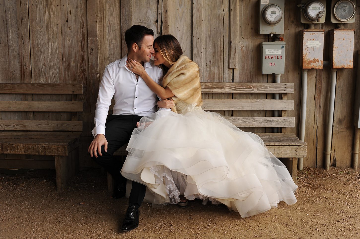 Bride amd groom are sitting on a bench in a romantic way