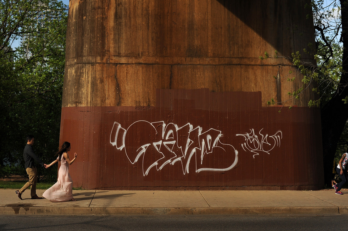 A couple is holding hands and passing under a bride in a downtown park in Austin TX during their engagement session