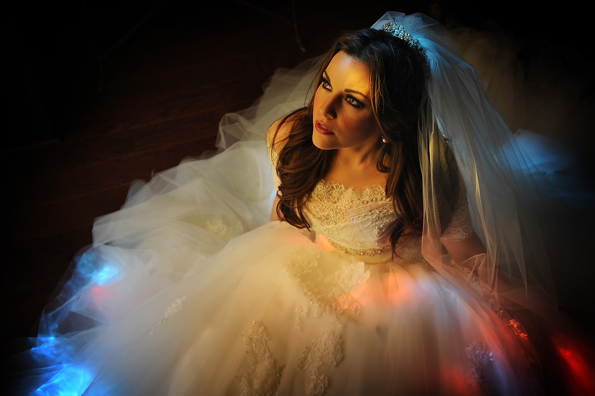 A bride is illuminated by different colors of light coming from a stained glas window in Austin Texas