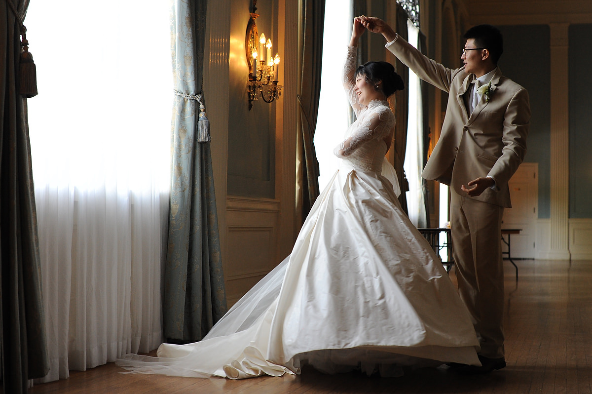 A couple is practicing their first dance new to one of the main hall windows in The Mansion wedding venue in Austin TX