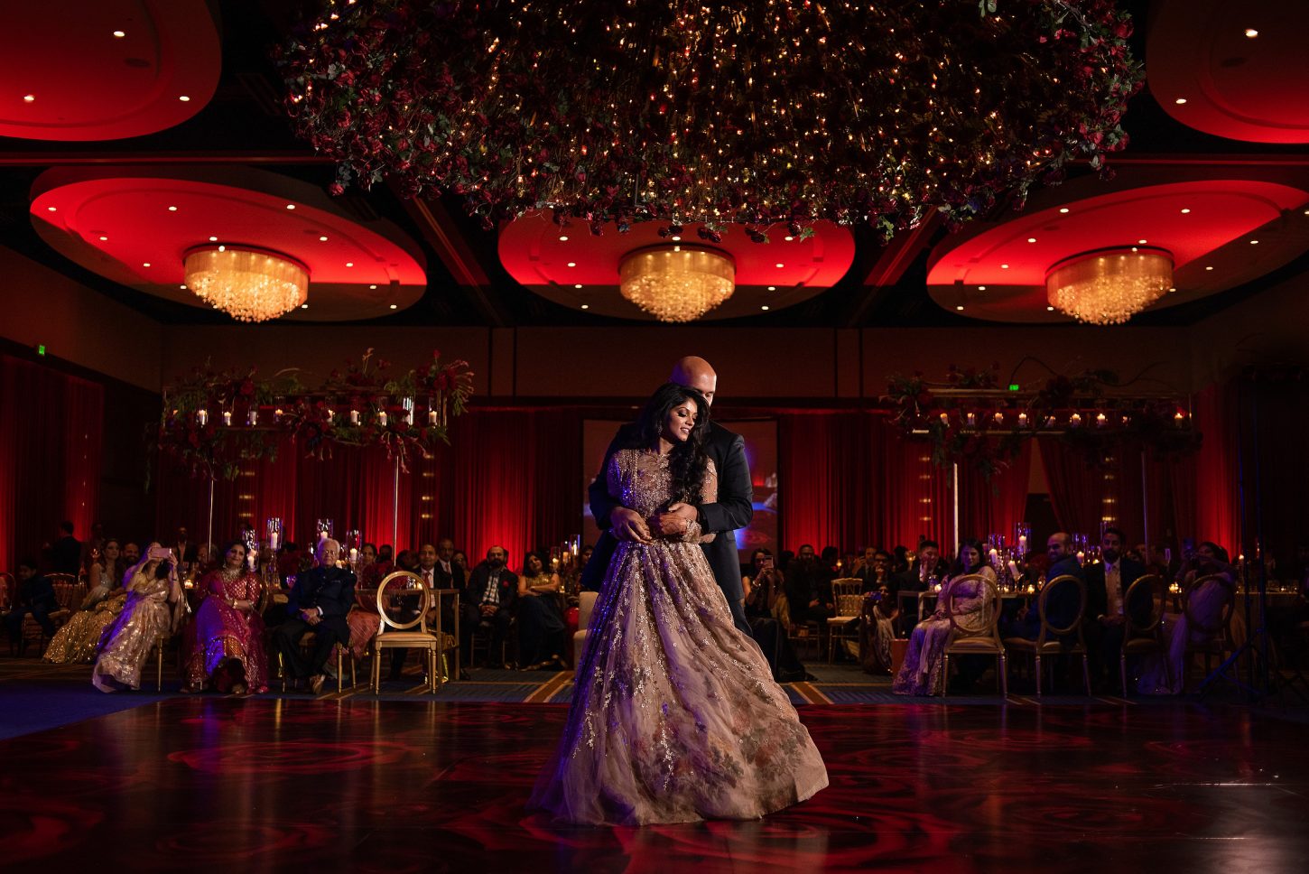 First dance of an indian weddiing in texas, the decoration and lighning is red and the couple dances in the middle