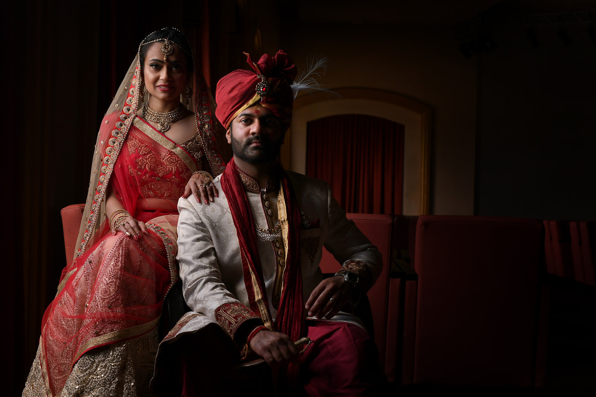 An indian wedding is dress in their traditional red gown and pose for their portrait